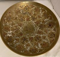 Top view of small brass bowl showing intricate floral design in brass, white, and red colors.