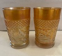 Two amber carnival glass tumblers side by side showing leaf and lattice pattern.