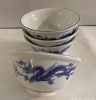 Side view of stacked bowls showing blue dragon design around exterior and gold trim on rims.