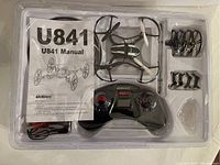 Top view of U841 drone, remote, manual, and accessories in plastic tray packaging.