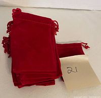 Stack of red velvet drawstring pouches with a note tagged '21'