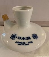 Front view of the white ceramic sake bottle showing blue floral design and Japan inscription.