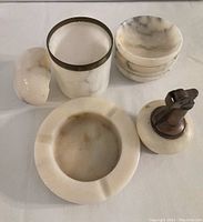 Top-down view of set laid flat showing lighter, ashtray, 4 bowls stacked and match holder with lid, all with white marbled appearance and chips visible on lighter base and match holder lid.