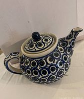 Full side view of blue and white Polish pottery teapot showing detailed circular floral patterns and ergonomic handle with lid