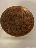 Top view showing detailed floral design in gold over red background inside the brass bowl.
