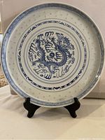Front of round porcelain tray with central blue dragon design and intricate border patterns on display stand