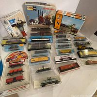 Full lot showing boxed Athearn Cottage & Mill, AHM guard tower, several Athearn freight cars and locomotives in packaging, and blister pak Old Timers 1860 set.