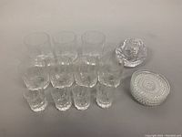 Full view of all 11 items including glasses, coasters, and candleholder on a gray surface