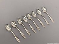 Eight spoons arranged in a row, top-down view