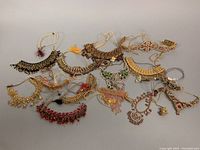 Top-down view of 11 assorted East Asian jewelry pieces arranged on gray background, showing detailed adorned necklaces with beadwork and metal decorations.