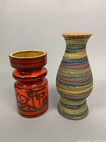 Two pottery vases side by side, showing size difference and color patterns: red and black Gouda Holland vase, and multicolor striped Italian vase.