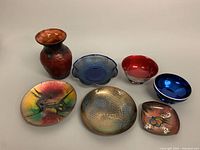 Full lot view showing all seven items including the metal bowls, enamel pieces, and glass vase arranged on a white surface.