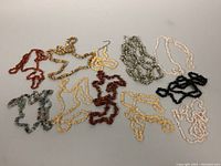 Eight vintage beaded semi-precious stone necklaces laid out on a flat surface showing variety of colors and stones.