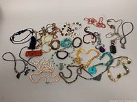 Photo showing an assortment of 20 vintage semi-precious stone beaded necklaces arranged together, displaying varied beads and styles.