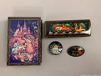 Top-down photo of all four items showing detailed painted scenes and overall condition.