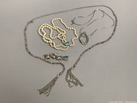Multiple vintage costume jewelry items on neutral surface including earrings and necklaces showing details of design.