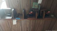 Photo showing multiple wooden bookends with carved wood figures in hats, placed on a wooden shelf.