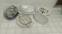 Various Corningware dishes, Edwin Knowles China plates and bowls, white ramekins and serving pieces arranged on countertop.