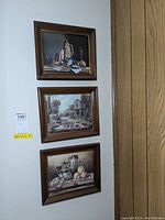 Three framed art pieces hung on wall, shows wood frames and visible scratch condition.