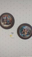 Two framed Hummel plates mounted on a wall, shown side by side.