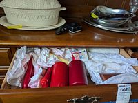 Open drawer showing several red pillar candles, wrapped taper candles, and boxed birthday candles on a wooden dresser.