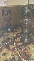 Pair of glass globe table lamps with metal eagle bases and tops on a patterned carpet