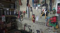Photo showing pegboard with various hand tools hanging and some tools arranged on shelves