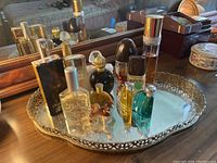 Vanity tray holding various perfume bottles and ceramic dog figurine on table in front of mirror.