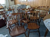 Set of 6 wooden spindle back dining chairs including 4 standard chairs and 2 captain's chairs grouped together in a room.