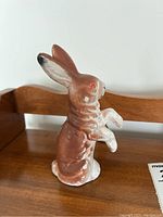 Side angle showing the brown paper mache bunny figurine standing upright on hind legs with raised front paws.