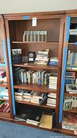 Wooden bookcase with books and magazine holders on shelves, showing overall structure and contents for reference.