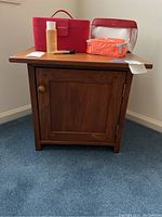 Front view of the wood cabinet with single door closed and items on top.