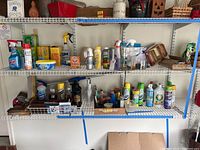 Wide shot of multiple shelves with various cleaning products arranged including spray bottles, powders, and small boxes.