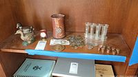 Wide shot of wooden shelf with ducks, desk clock, coin holder, coin tubes, coins and storage items