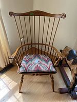 Full front view of the Ethan Allen Windsor style wooden armchair with spindle back and patterned seat cushion on hardwood floor.