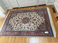 Full view of the 4.5x6.5 ft hand knotted wool area rug with fringe, showing floral and medallion patterns in earthy tones on hardwood floor.