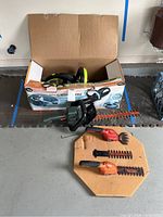 Garden Groom Pro box with electric hedge trimmer and two Black & Decker hand trimmers on floor