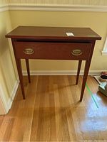 Front view of the Wayne K Kramer wood side table showing one drawer and tapered legs on hardwood floor.