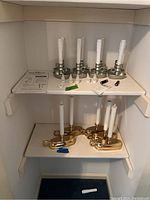 Shelf with two sets of Plow & Hearth battery operated candle holders; silver-tone on top shelf with accessories, brass-tone on bottom shelf