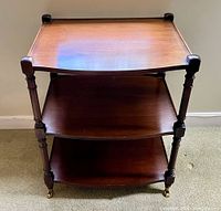 Front view of the 3-tier wooden rolling cart showing turned legs and curved shelf edges.