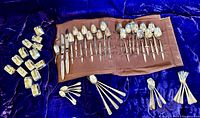 Full view of flatware pieces with napkin rings on dark blue velvet surface.