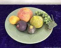 Top and front view showing alabaster fruit and hardstone grape cluster on celadon plate.