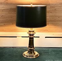 Overall view of the brass desk lamp showing polished brass base and greenish-black shade.