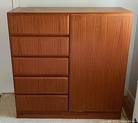 Front view of Danish teak wardrobe showing five drawers on left and closed cabinet door on right.