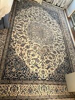 Full view of rug laid on floor showing cream field and border