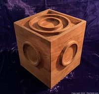 Front and side view of the cube-shaped teak ice bucket showing raised circular designs on all visible sides and concentric circle design on the lid.