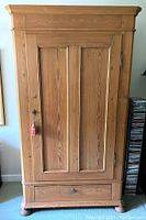 Full frontal view of the solid pine office armoire showing panelled door with key and drawer at the bottom.