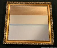 Full view of square giltwood mirror with ornate scrolled detailed frame and reflective glass.