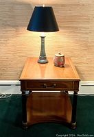 Front view showing end table top with drawer, lower shelf, lamp and jar