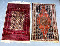 Two small tribal rugs displayed side by side on the floor showing different patterns and colors, both hand-knotted with fringes on the ends.
